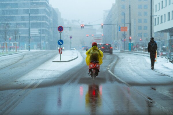 motorcyclist-with-a-raincoat-drives-along-a-snow-covered-road