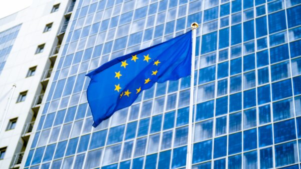 image-of-eu-flag-fluttering-on-wind-against-high-business-office-building-made-of-concerete-and